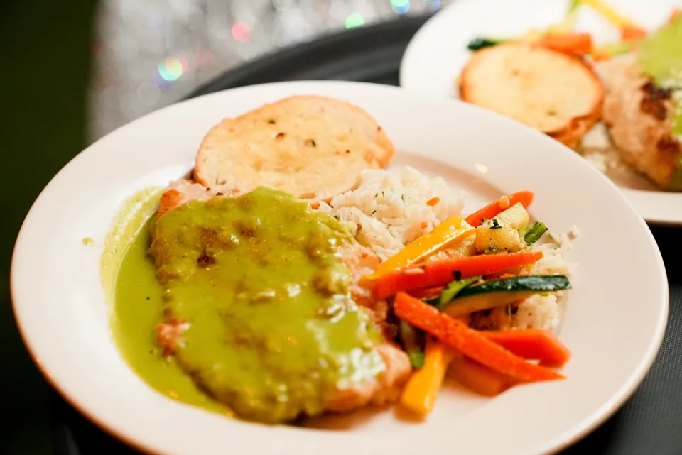 Plated entrée with green sauce, rice and vegetables